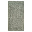 Green Capel Worcester Braided rug with intricate patterns and braided construction on a hardwood floor, enhancing a classic home setting.